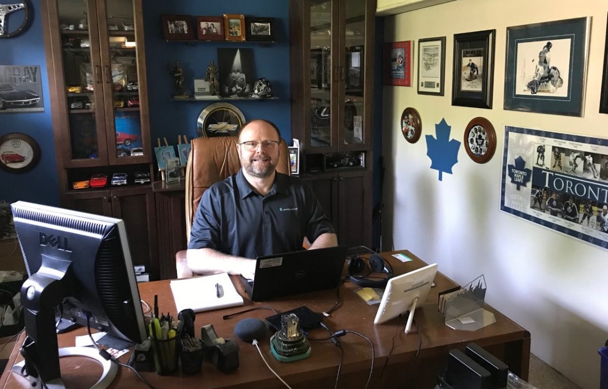 Richard, Account Manager for Pepperl+Fuchs in Toronto, sits in his home office. The room has dark brown furniture and many pictures on the wall. He sits in front of his laptop and smiles at the camera.