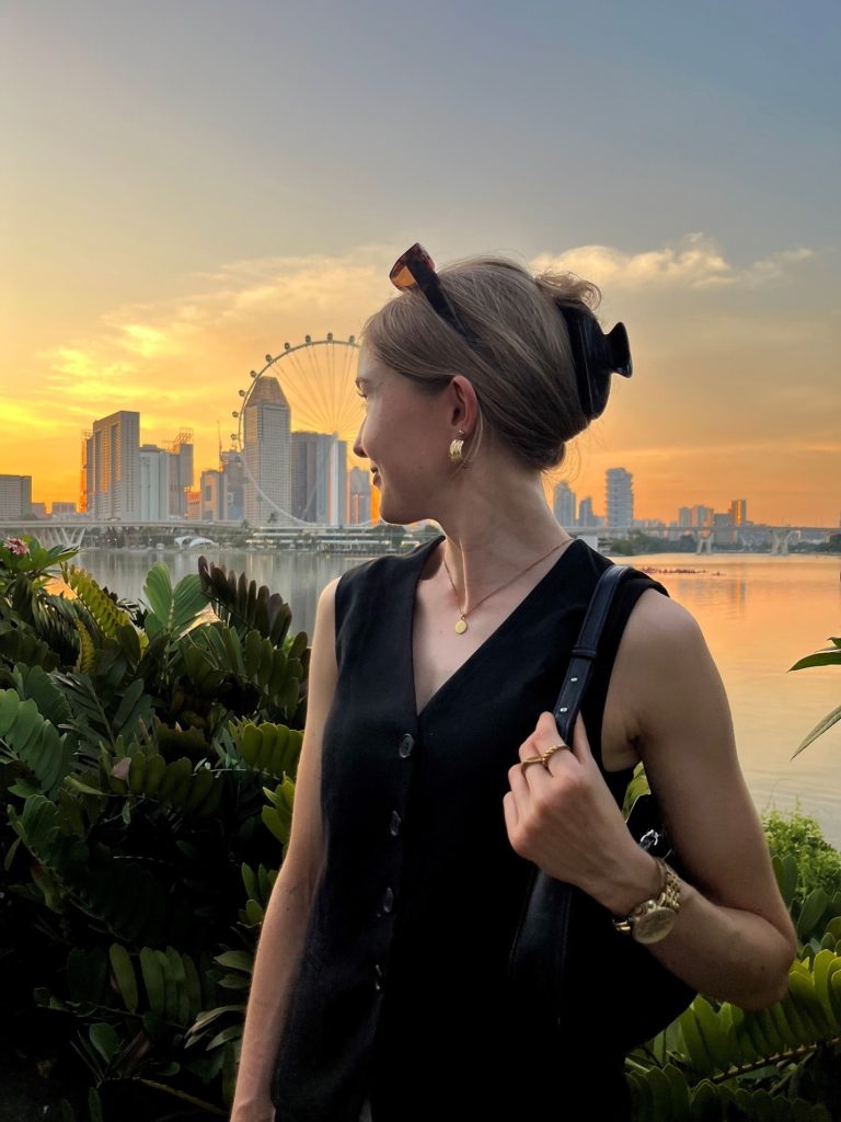 Janine is turning away from the camera. In the background, you can see the Singapore skyline. The sun is just setting.