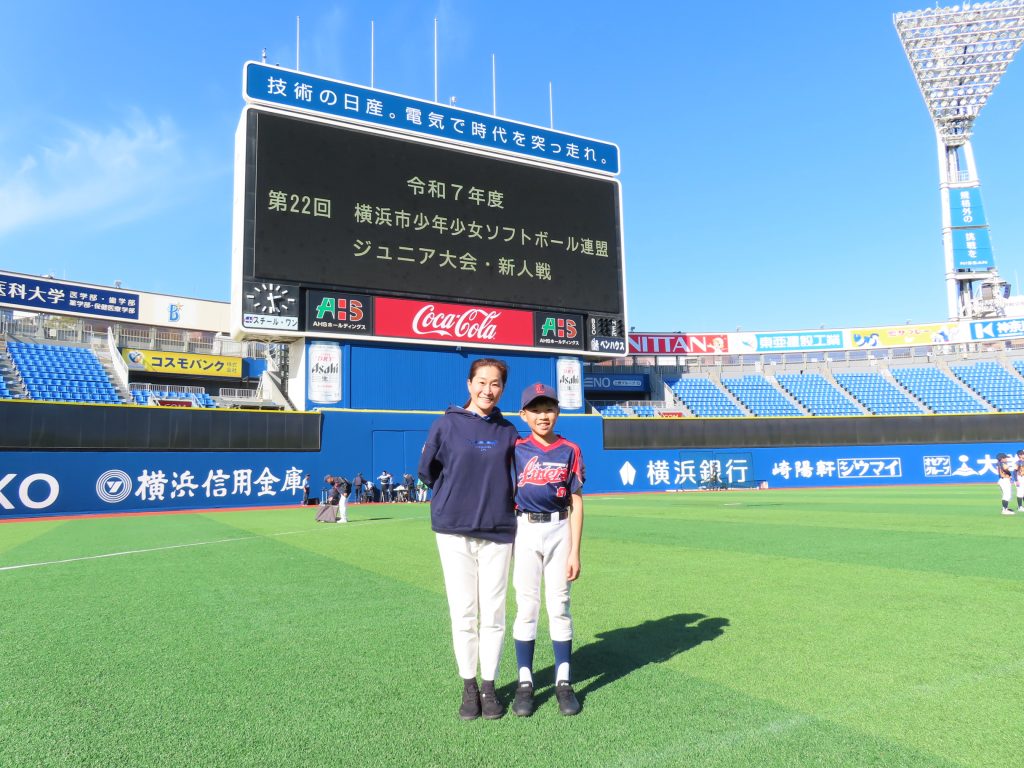 Aya and one of her children are at the stadium. They are standing in the middle of the pitch.